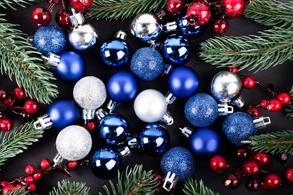 Vista superior de las bolas de Navidad, cuentas rojas y ramas de pino sobre fondo negro - Foto, Imagen