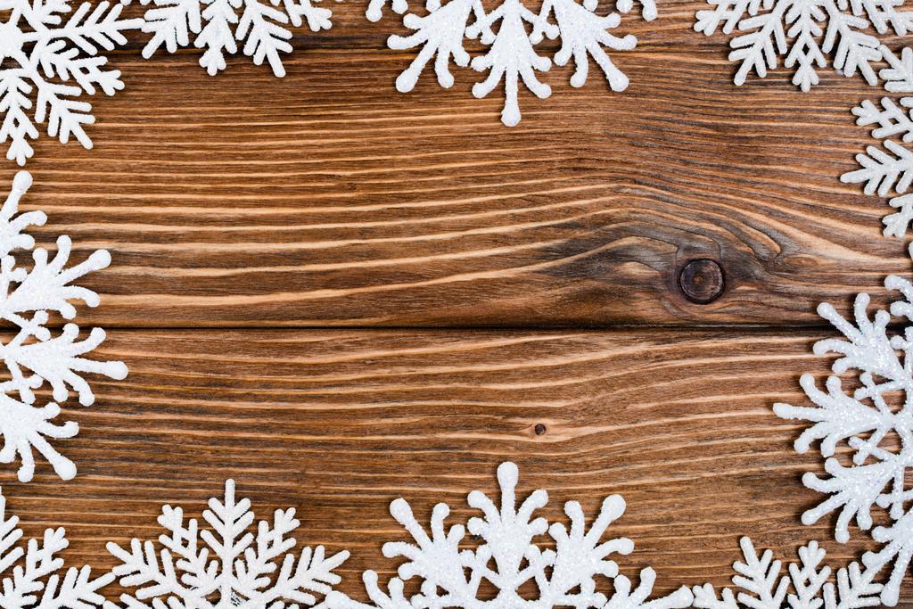 Flat lay com flocos de neve decorativos em fundo de madeira marrom, conceito de ano novo - Foto, Imagem