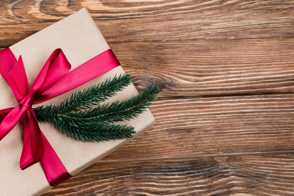Top view of gift box with pink ribbon and pine branch on brown wooden background, new year concept - Photo, Image