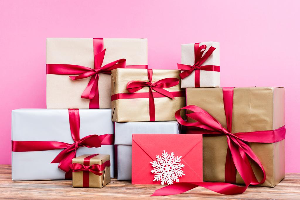 Surface level of gift presents, red envelope and decorative snowflake on pink background - Photo, Image