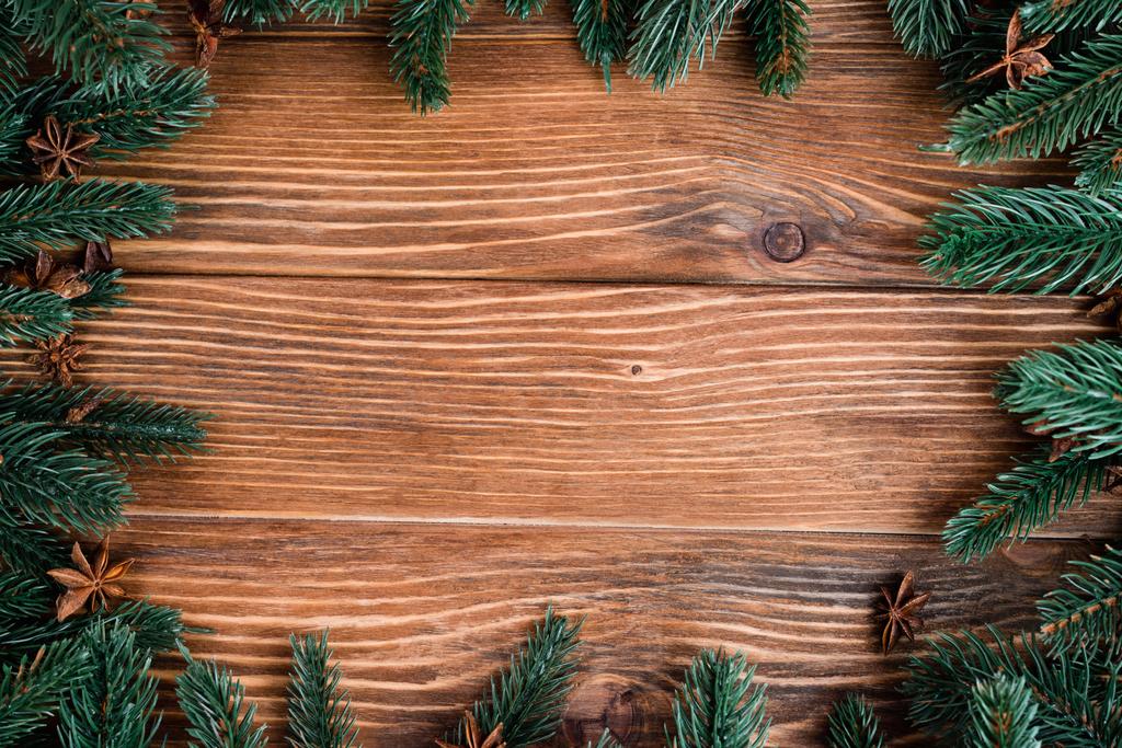 Flat lay with pine branches and anise stars on brown wooden background, new year concept - Photo, Image