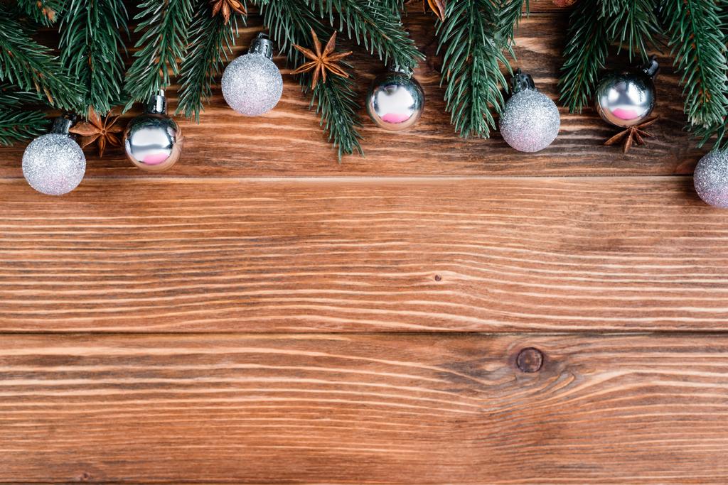 Top view of pine branches, baubles and anise stars on brown wooden background, new year concept - Photo, Image