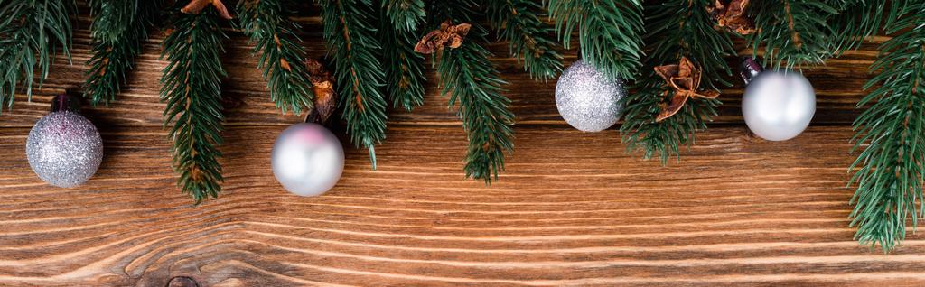 Bovenaanzicht van kerstballen, anijssterren en dennentakken op bruine houten ondergrond, spandoek - Foto, afbeelding