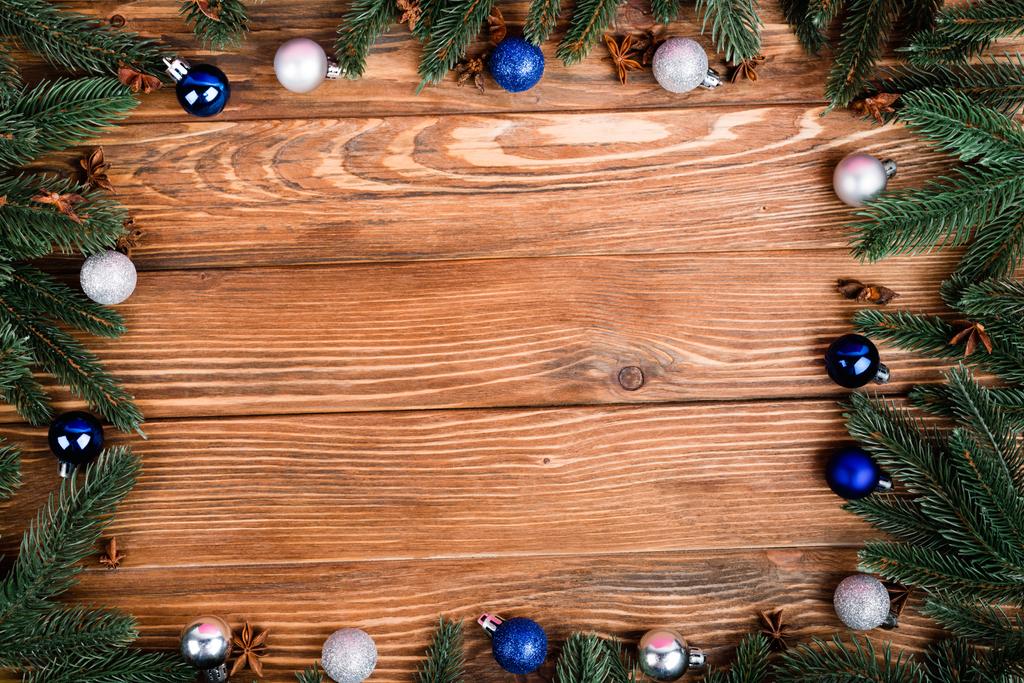 Flache Lage mit Tannenzweigen, Weihnachtskugeln und Anissternen auf braunem Holzgrund, Neujahrskonzept - Foto, Bild