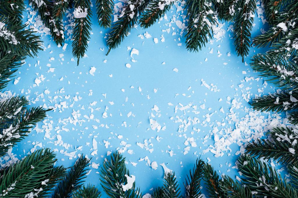 Плоский ліжко з сосновими гілками та штучним снігом на синьому фоні, концепція нового року
 - Фото, зображення