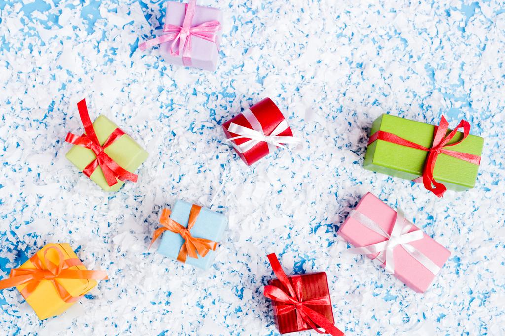Draufsicht auf kleine Geschenkboxen mit Kunstschnee auf blauem Hintergrund, Neujahrskonzept - Foto, Bild