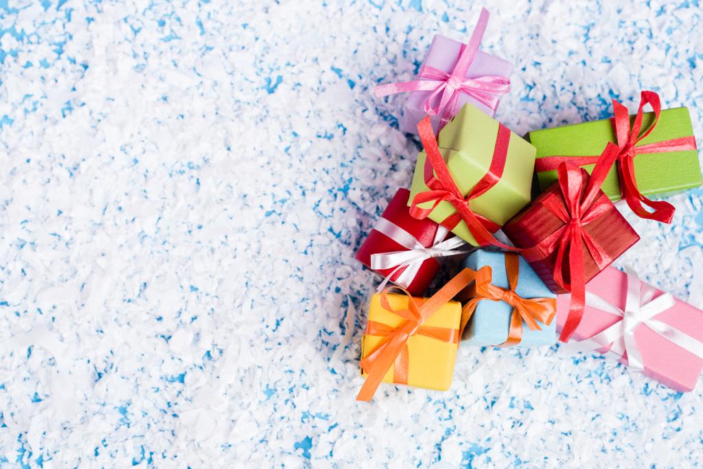 Top view of little gifts with artificial snow on blue background, new year concept - Photo, Image