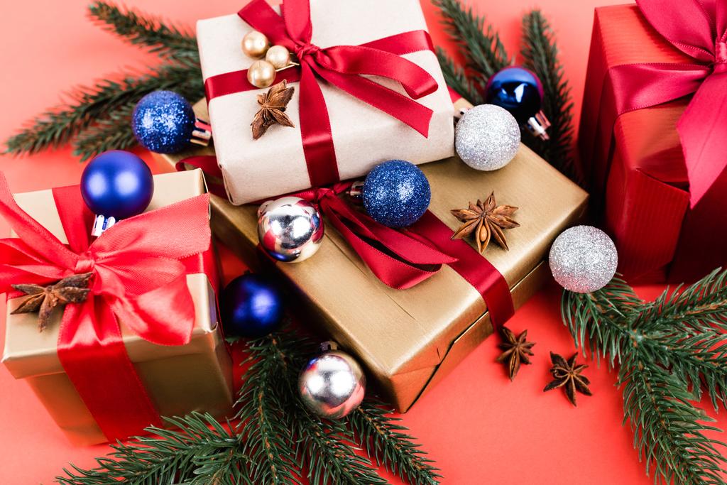 Geschenkdozen met kerstballen, anijssterren en dennentakken op rode achtergrond - Foto, afbeelding