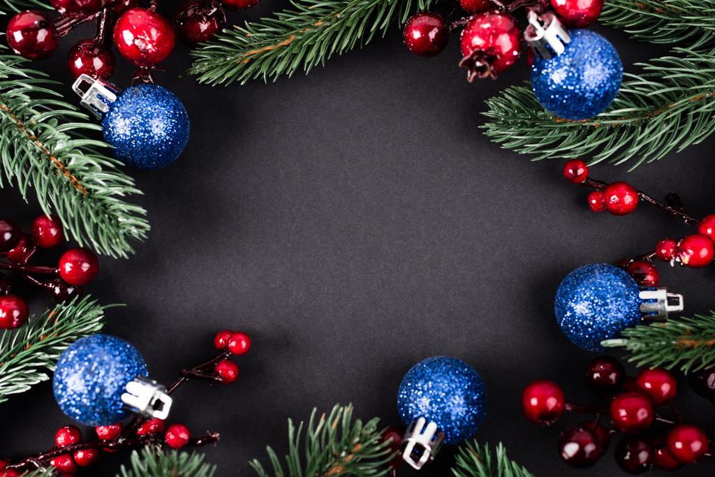 黒を背景に松の枝、人工ベリー、クリスマスボールのトップビュー - 写真・画像