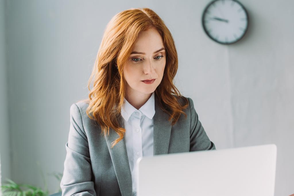 Focused businesswoman looking at laptop on blurred foreground - Photo, Image