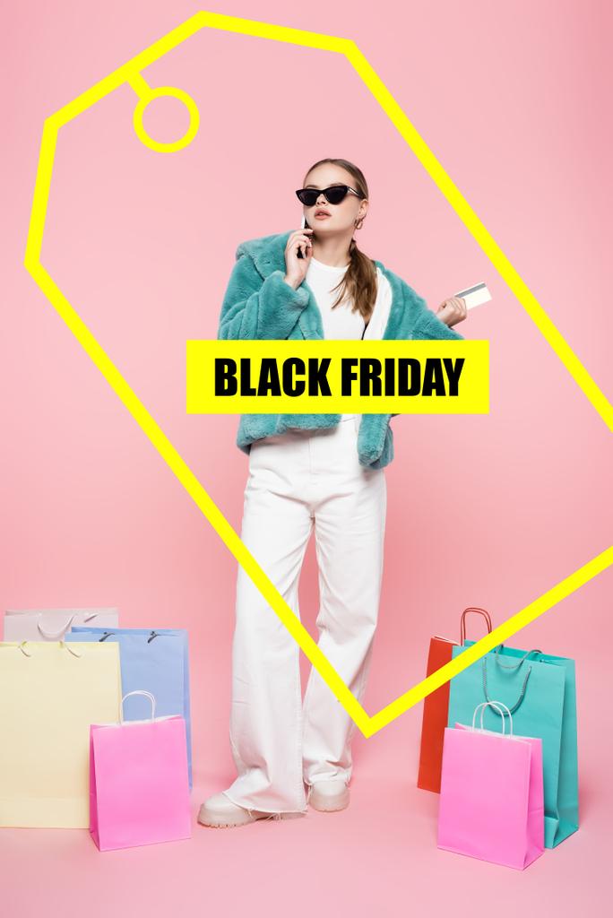femme élégante dans des lunettes de soleil parler sur smartphone et tenant la carte de crédit près des sacs à provisions et noir vendredi lettrage sur rose - Photo, image