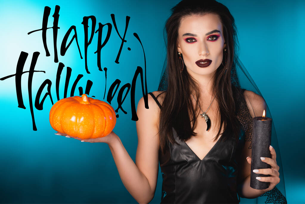 молода бліда жінка з чорним макіяжем і завісою тримає свічку і гарбуз біля щасливого Хеллоуїна на синьому
 - Фото, зображення