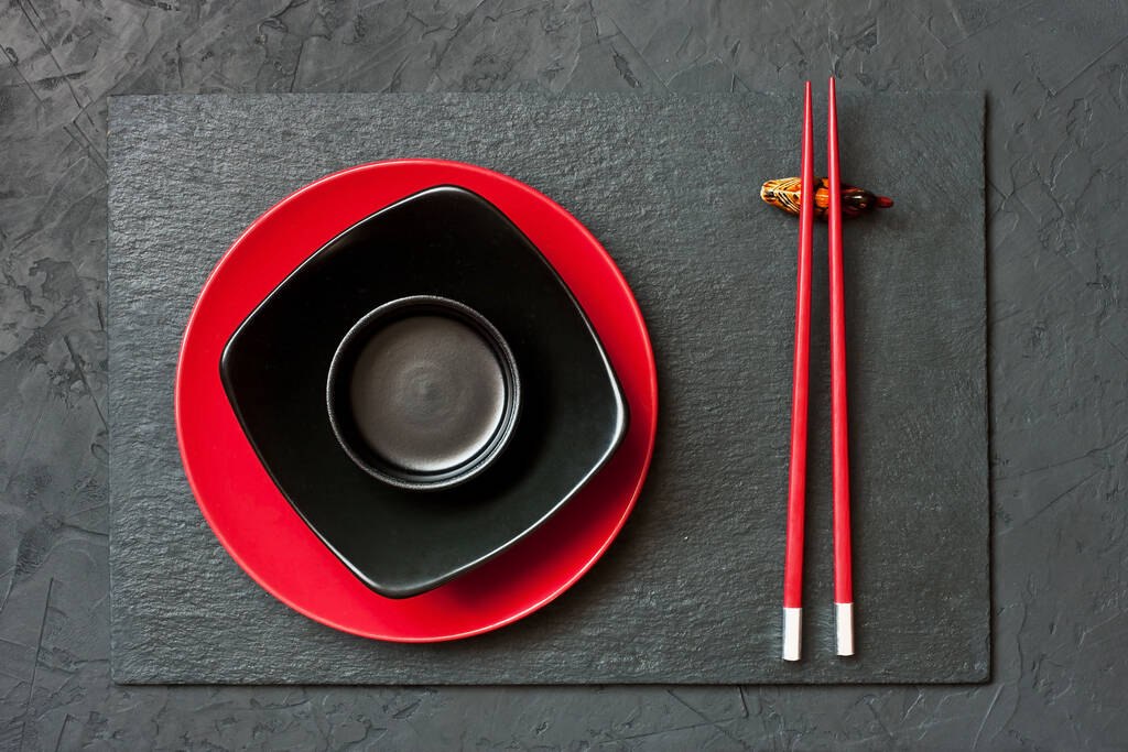 暗い背景に箸とセラミック皿(プレート)の木製のペア。テキスト、画像、広告のためのスペース。アジア風の料理メニュー - 写真・画像