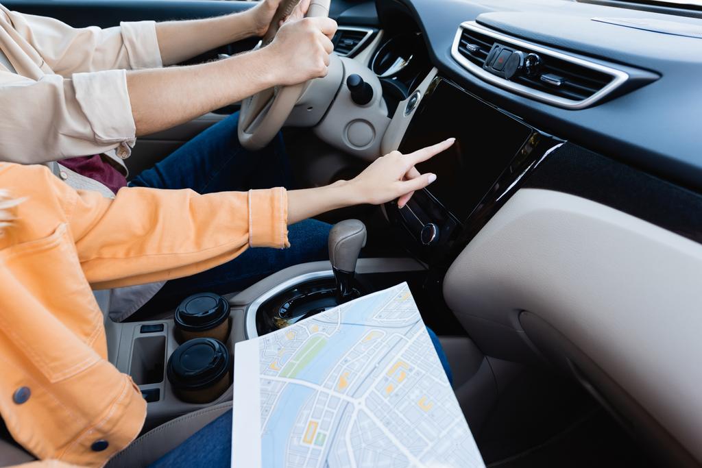 Vista recortada de la mujer con el mapa usando el sistema de audio mientras el marido conduce el coche  - Foto, Imagen
