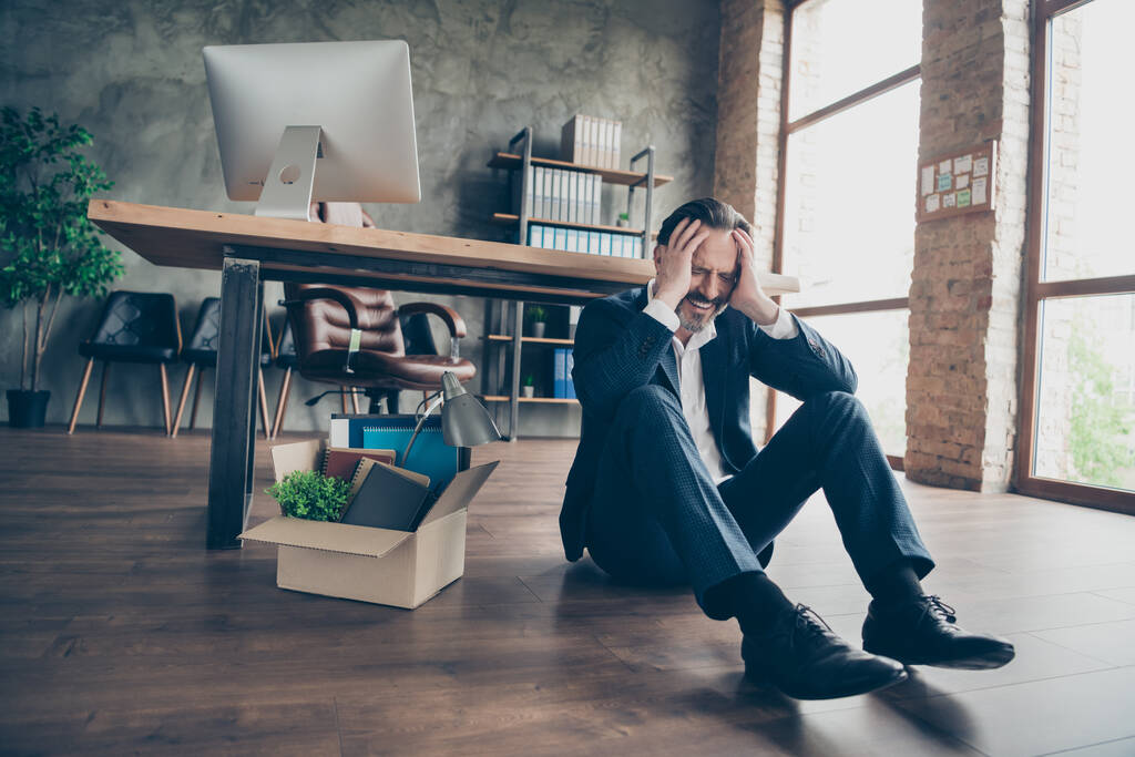 Photo of dismissed despair sad worker mature guy fail fired agent lost job packed belongings box financial crisis sit floor wooden parquet beeless cry workstation office indoors - Fotografie, Obrázek