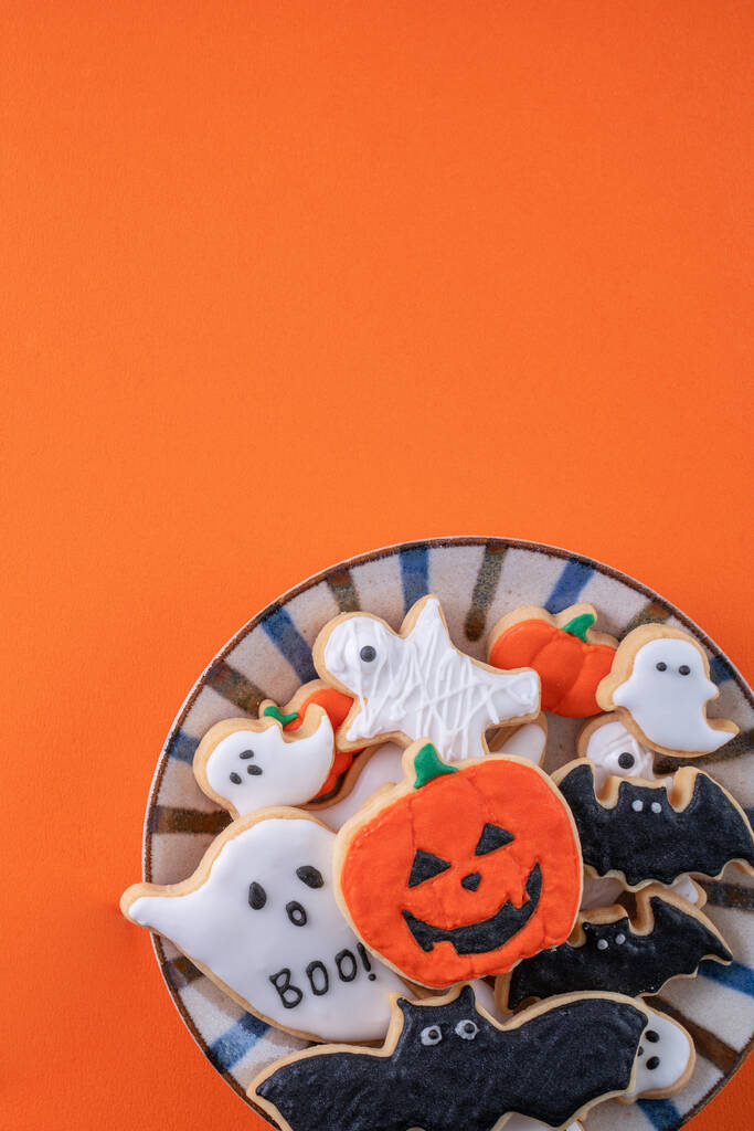 Draufsicht auf Halloween festlich dekorierte Puderzucker-Plätzchen auf orangefarbenem Hintergrund mit Kopierraum und flachem Layout. - Foto, Bild