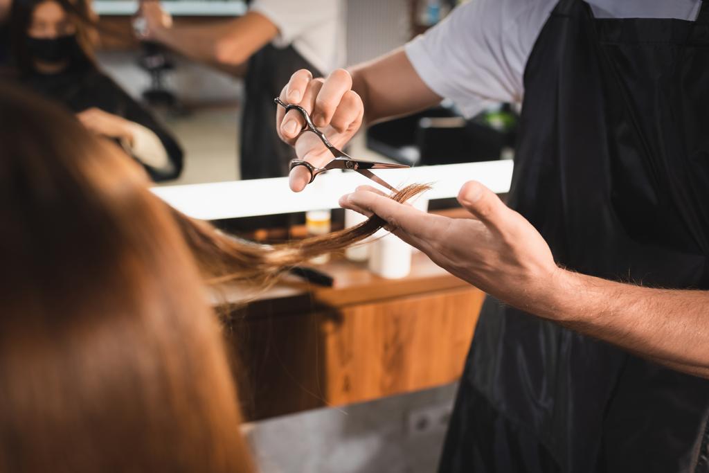 vista recortada de peluquería corte de pelo del cliente en primer plano borrosa - Foto, Imagen