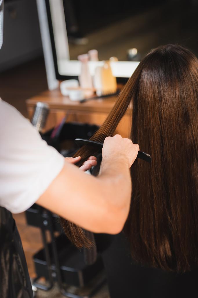 fryzjer czesanie włosy kobiety na niewyraźnym pierwszym planie - Zdjęcie, obraz
