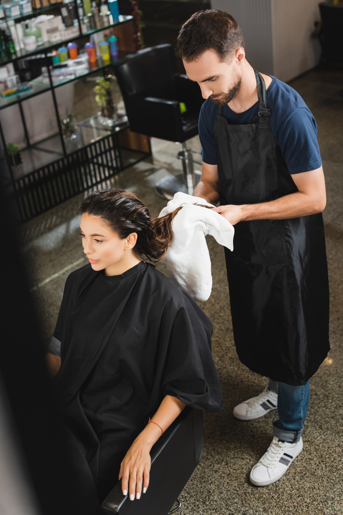 high angle view of barber wiping hair of woman with towel, blurred foreground - Photo, Image