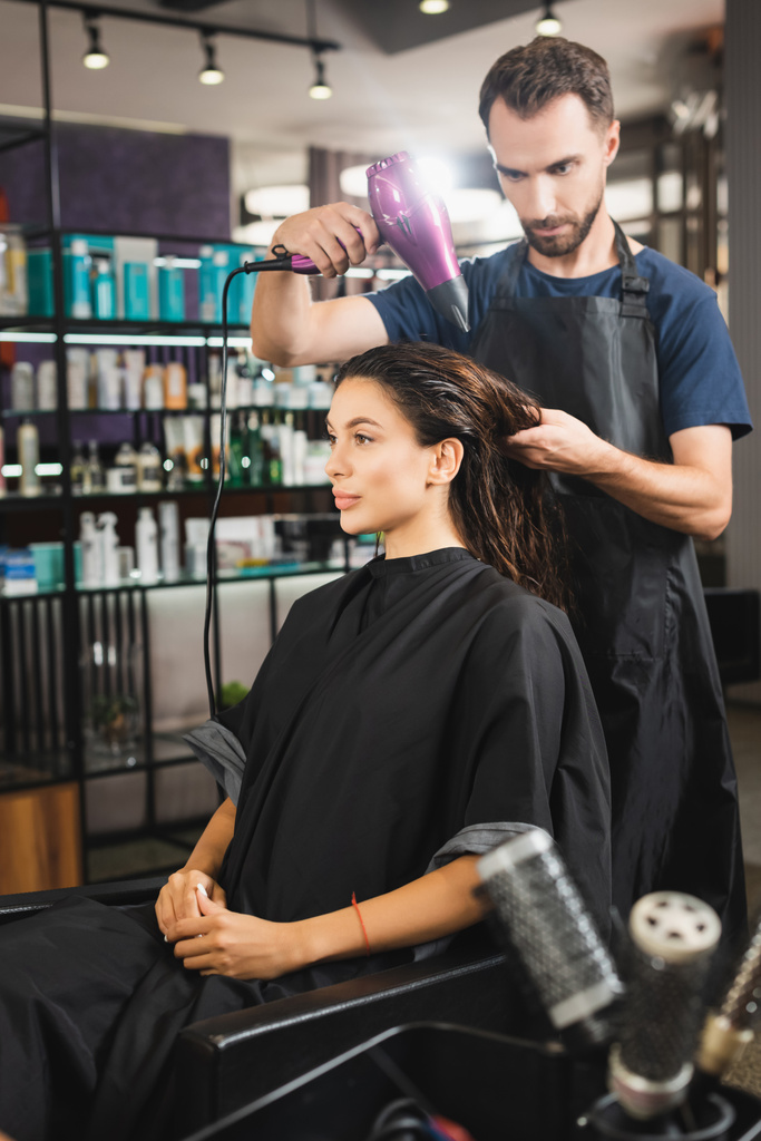 joven peluquero secado pelo de mujer cerca de peines en primer plano borrosa - Foto, Imagen