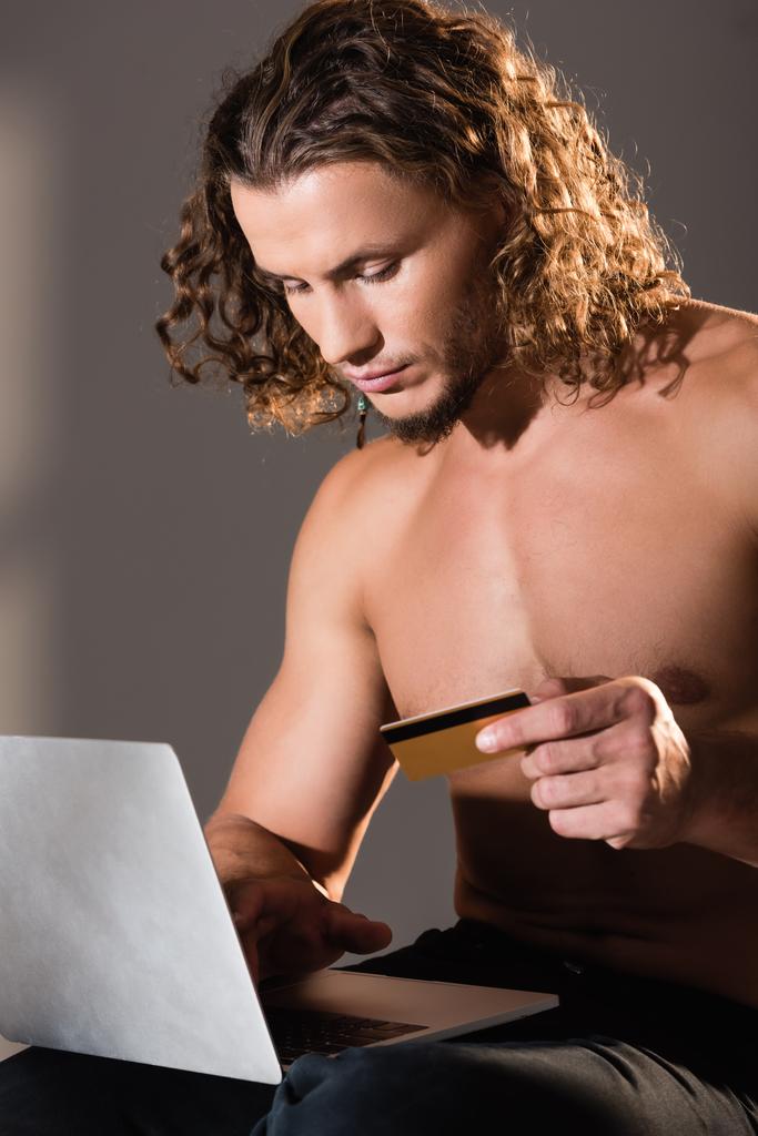 sexy bez trička muž drží notebook a kreditní kartu - Fotografie, Obrázek