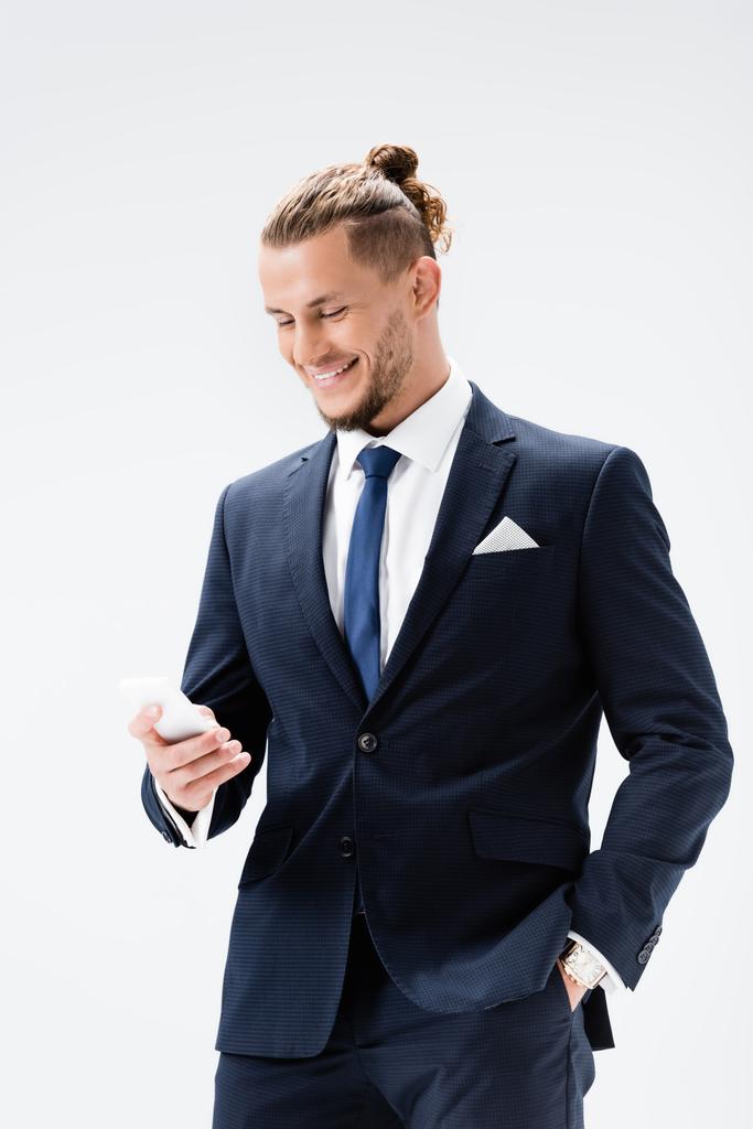 Lächelnder junger Geschäftsmann im Anzug mit Smartphone auf weißem Hintergrund - Foto, Bild