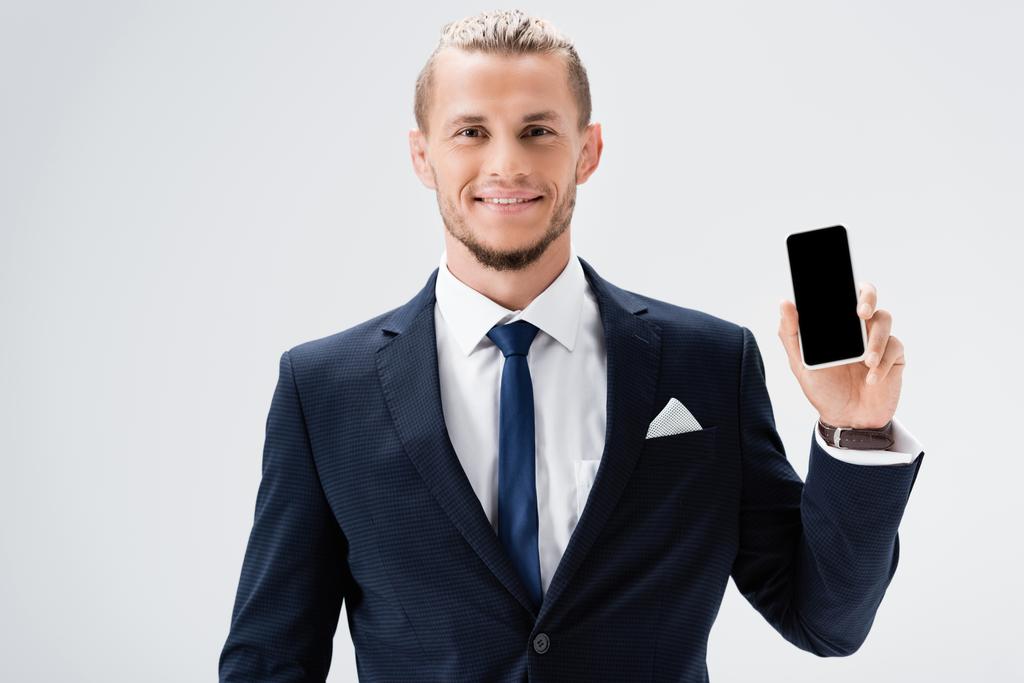 hymyilevä nuori liikemies puku esittää älypuhelin eristetty valkoinen - Valokuva, kuva