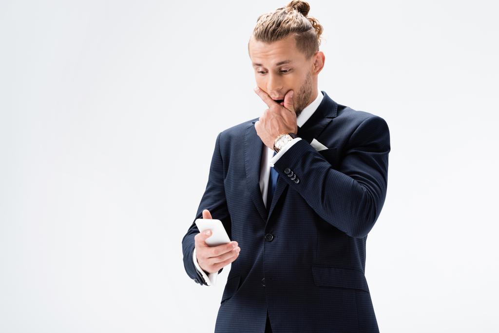 σύγχυση νεαρός επιχειρηματίας στο κοστούμι με smartphone απομονώνονται σε λευκό - Φωτογραφία, εικόνα