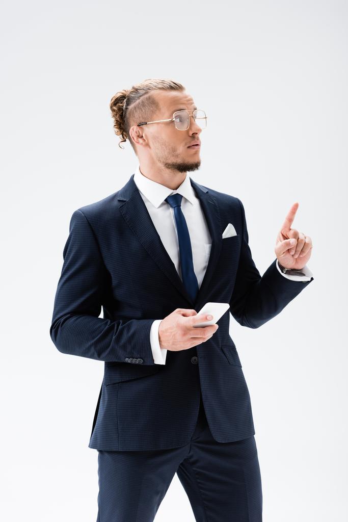 mladý podnikatel v obleku a brýle ukazuje nahoru izolované na bílém - Fotografie, Obrázek