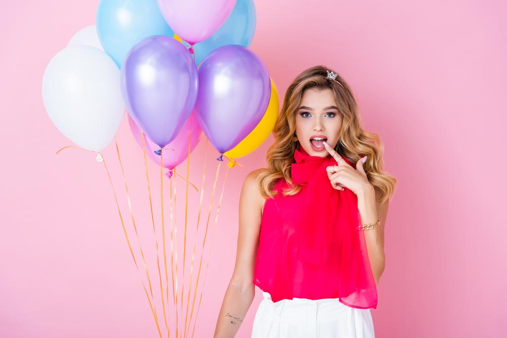 elegante donna sorpresa in corona con palloncini su sfondo rosa - Foto, immagini