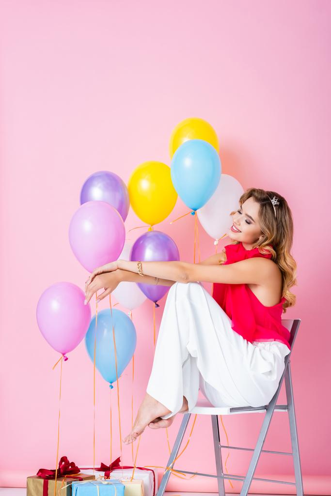елегантна щаслива жінка в короні з повітряними кулями на рожевому фоні
 - Фото, зображення