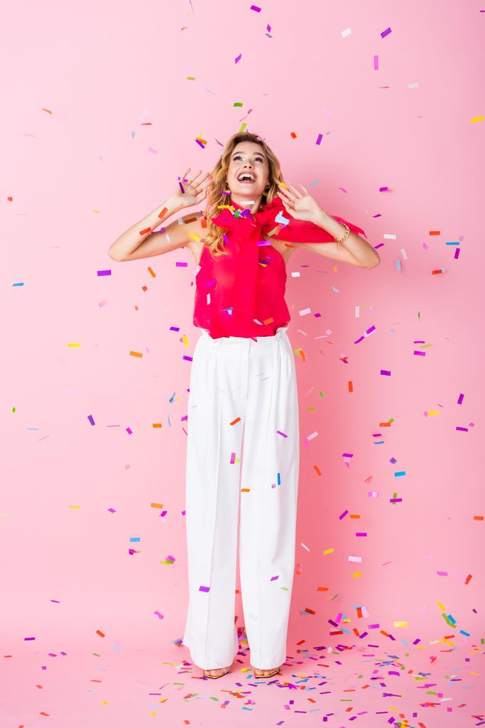élégante femme heureuse en couronne sous confettis sur fond rose - Photo, image