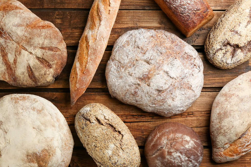 Różne rodzaje świeżego chleba na drewnianym stole, układanie płaskie - Zdjęcie, obraz