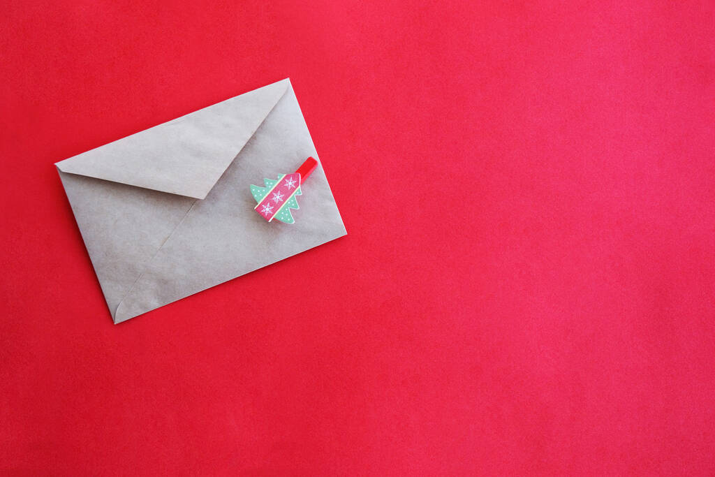 Sobre de papel con una espina de arenque sobre un fondo rojo, primer plano. Carta a Santa Claus. - Foto, Imagen