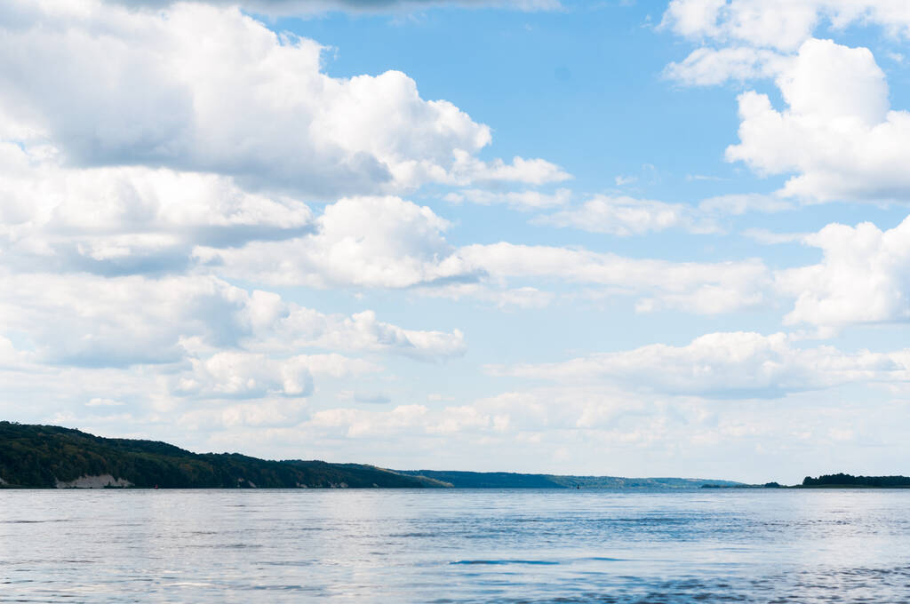 prachtig rustig landschap van water, heuvels met bomen en blauwe lucht met wolken op de rivier - Foto, afbeelding