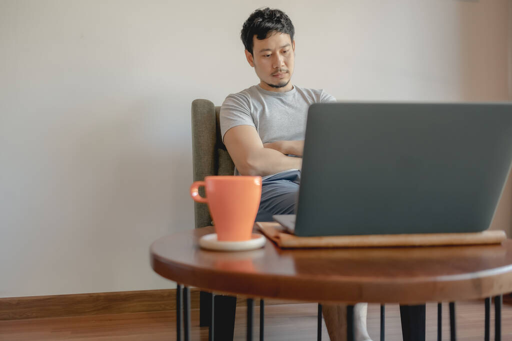 Чоловік працює зі своїм ноутбуком і п'є каву.. - Фото, зображення