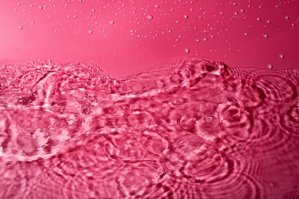 salpicadura de agua sobre un fondo rojo. Fondo de pantalla abstracto - Foto, imagen