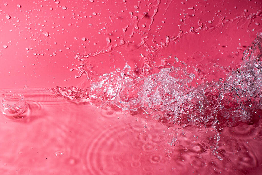 salpicadura de agua sobre un fondo rojo. Fondo de pantalla abstracto - Foto, Imagen