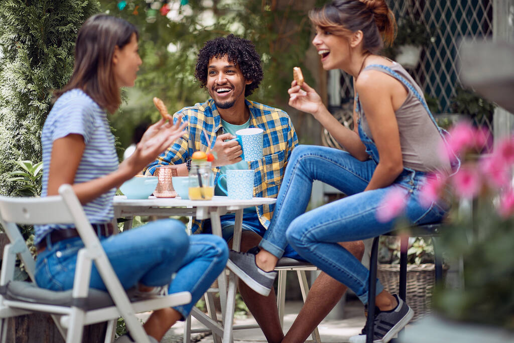 Amigos alegres disfrutando de un aperitivo en el patio trasero del bar con un clima hermoso. Tiempo de amistad de calidad juntos - Foto, imagen
