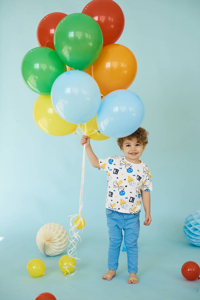 Mavi arka planda balonlarla poz veren neşeli çocuk portresi - Fotoğraf, Görsel