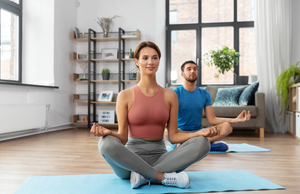 Yoga poz veren çift evde meditasyon yapıyor. - Fotoğraf, Görsel