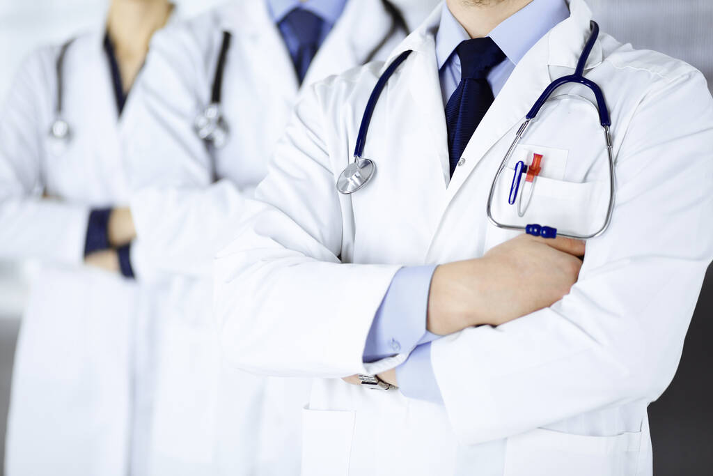Moderne dokters staan als een team met gekruiste armen en stethoscopen in het ziekenhuiskantoor. Artsen klaar om patiënten te onderzoeken en te helpen. Medische hulp, verzekering in de gezondheidszorg, beste desease - Foto, afbeelding
