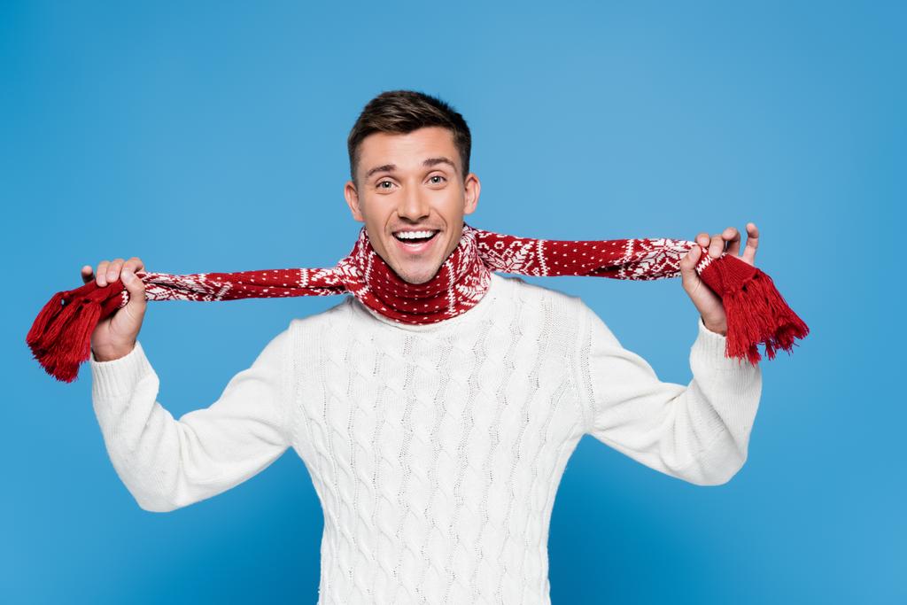 陽気な男でセーター保持スカーフと見ますカメラオン青の背景 - 写真・画像