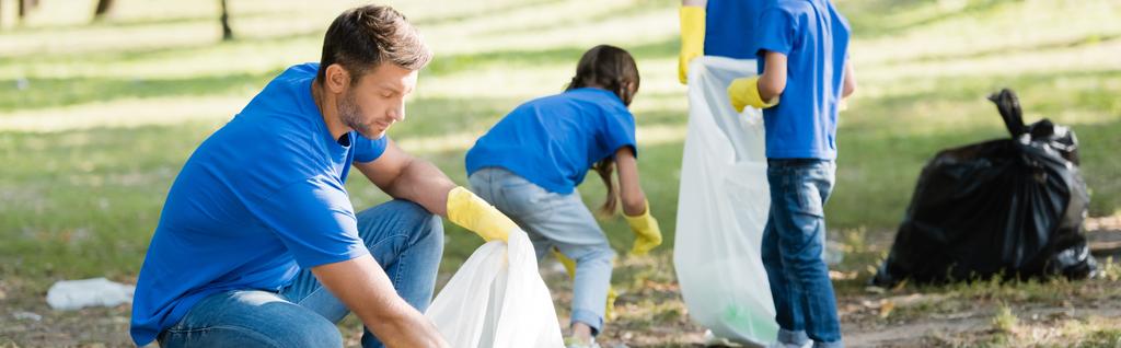 Familie von Freiwilligen sammelt Müll in recycelten Plastiktüten, Umweltkonzept, Transparent - Foto, Bild