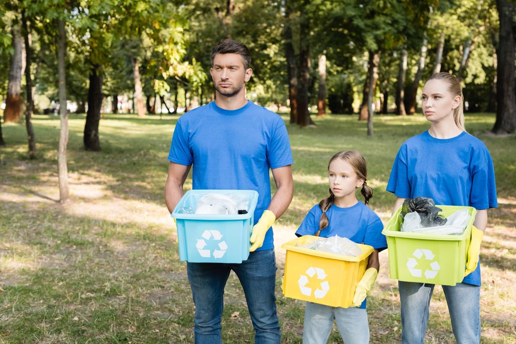 famille de bénévoles tenant des conteneurs avec des panneaux de recyclage, plein de déchets en plastique, concept écologique - Photo, image