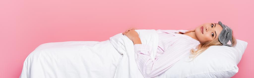 fiatal nő pizsamában feküdt párnán takaró rózsaszín háttér, banner  - Fotó, kép