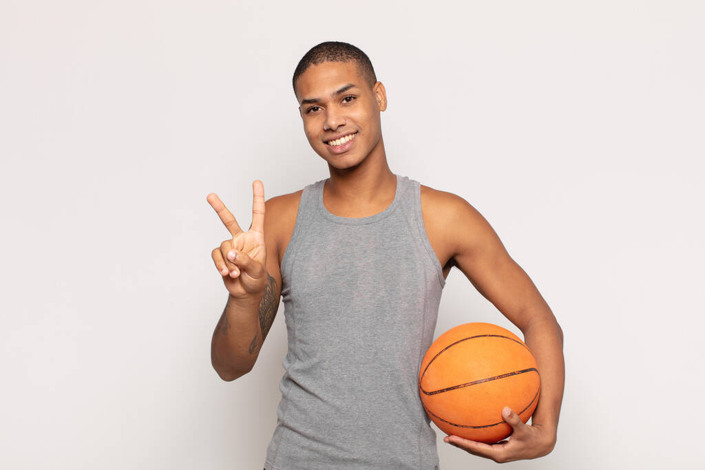 fiatal fekete férfi mosolyog és barátságos, mutatja a második vagy második kéz előre, visszaszámlálás - Fotó, kép