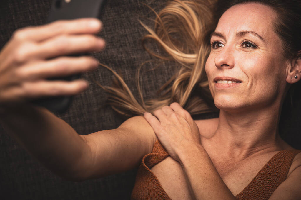 Šťastná žena středního věku brát selfie se svým chytrým telefonem doma - Fotografie, Obrázek