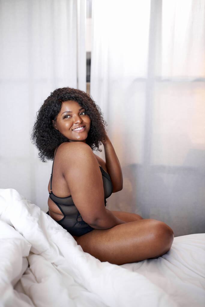 paffuto donna africana in lingerie si siede sul letto al mattino - Foto, immagini