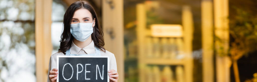fleuriste positif dans le panneau de maintien de masque médical avec lettrage ouvert près de la boutique de fleurs sur fond flou, bannière - Photo, image